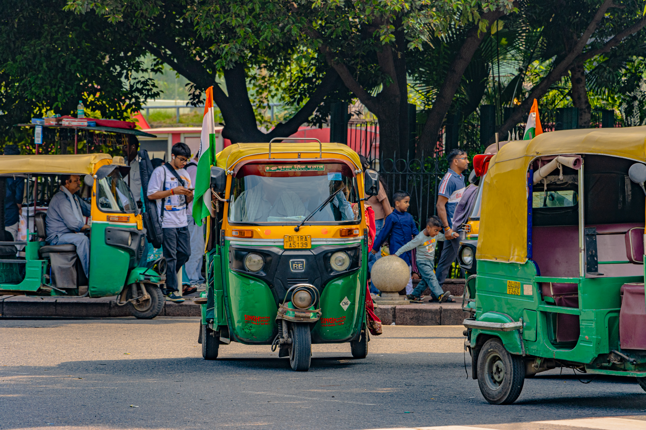 Vibrant street scene featuring auto rickshaws and pedestrians in New Delhi, India.